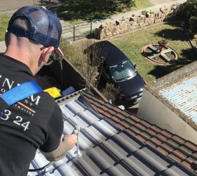 Painter spraying the roof in Monument colour during a residential repaint in Castle Cove