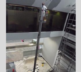 Platinum painter elevated on Genie electric lift repainting Northbridge commercial office ceiling.