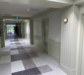 Corridor View – Light-filled hallway with paneling and patterned flooring.