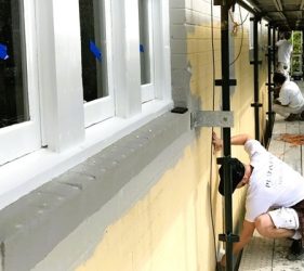 Painter preparing facade from scaffolding during strata restoration project in Kirribilli
