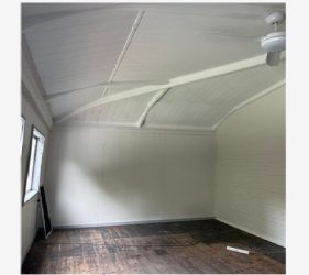 Restored Dulwich Hill bedroom featuring vaulted ceiling, exposed beams, and dark timber floors