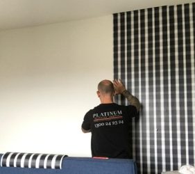 Installer working on black check wallpaper in Balmain room