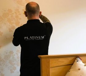 Wallpaper installer smoothing floral print in Rose Bay bedroom