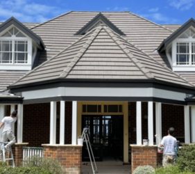 Painter applying fresh exterior paint to the front elevation of a Forestville home during restoration