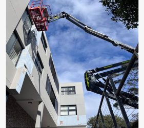 Platinum Painting team removing damaged render from a strata building facade in Mona Vale using a boom lift