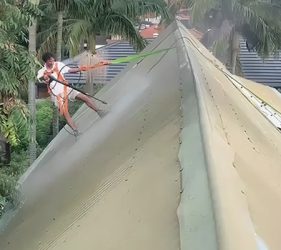 Jet washing a steep Colorbond roof with harnesses and safety ropes before painting in Sydney.
