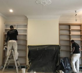 Two painters working on custom-built bookcases in a Surrey Hills residential home.