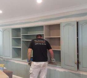 Painter refinishing cabinetry inside a Surrey Hills residential home.