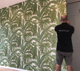 Installer aligning tropical green wallpaper in Mosman lounge