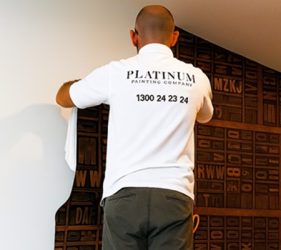 Professional painter installing custom feature wallpaper during an office painting project in Crows Nest, Sydney