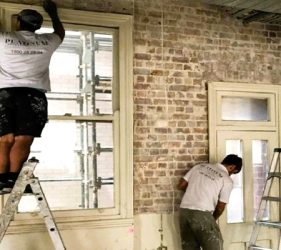 Platinum Painting team preparing woodwork and walls in gutted Surry Hills office with exposed brick on construction site